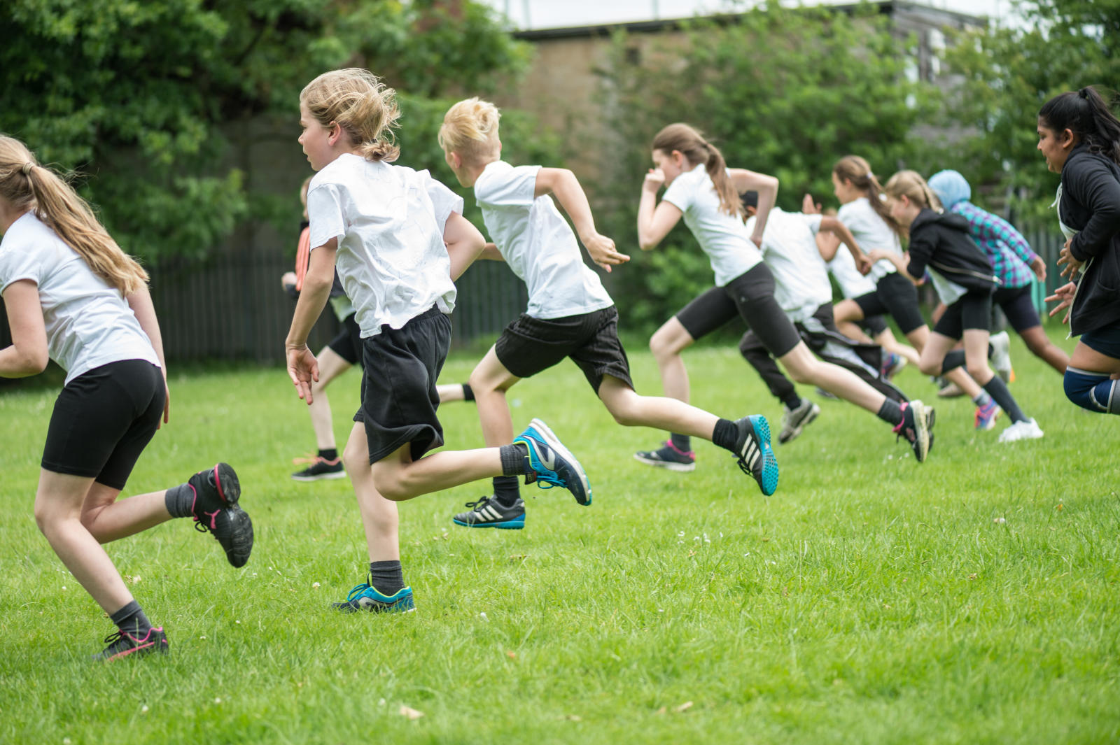 children running in a field dressed in school uniform